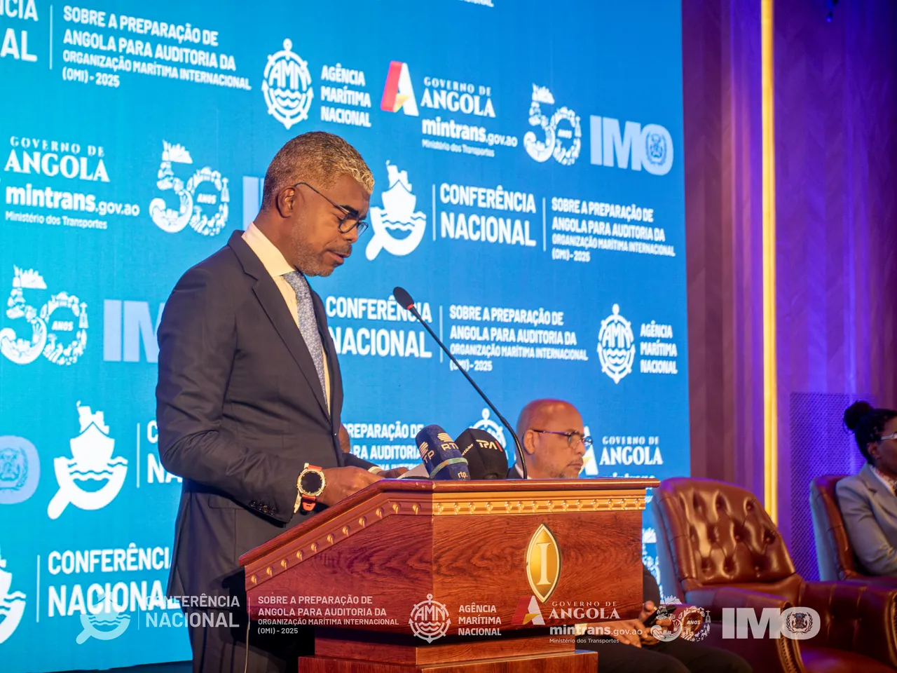 Discurso de abertura, com o backdrop da conferência em fundo.