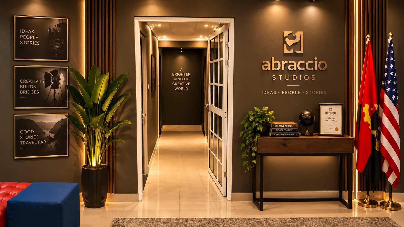 Corredor do estúdio: o nome da Abraccio na parede da direita, bandeiras ao canto, uma planta alta à esquerda e a porta envidraçada aberta ao fundo.